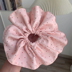 Macro detail of large pink polka dot hair scrunchie with floral jacquard texture