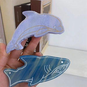 Détail de pinces à cheveux dauphin et requin en acétate marbré avec œil en strass brillant