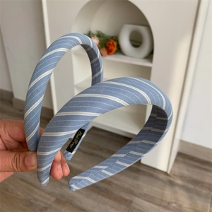 Close-up of light blue striped fabric headbands showing hand-held detail and inner brand label