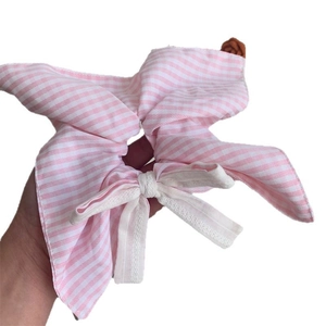 Pink and white striped cotton scrunchie with a white lace bow detail on a plain background