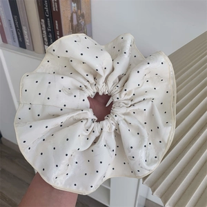 Close-up of oversized beige polka dot satin scrunchie with subtle jacquard pattern