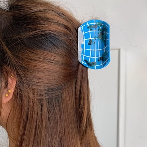 Side view of a creative globe-shaped acetate hair claw clip worn on a woman's ponytail