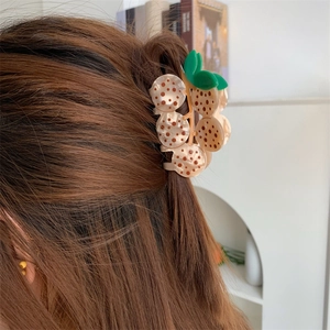 Detail of creative fruit shaped acetate hair claw clip with leaf accent in hair