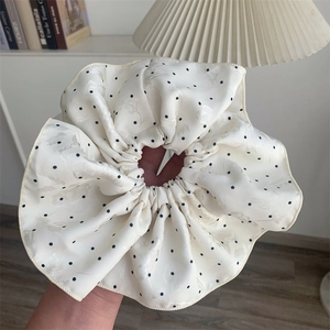 Detailed macro view of beige satin polka dot scrunchie with subtle jacquard texture
