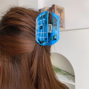 Detailed view of the creative globe pattern acetate hair claw clip on brown hair