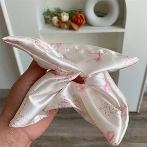 Detail of pink satin scrunchie featuring sweet bow patterns and delicate lace edges