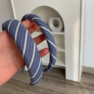 Close-up of a padded blue plaid headband with white diagonal stripes for hair styling