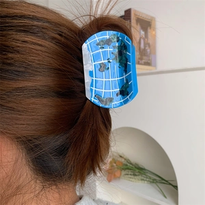 Detail of world map globe hair claw clip in blue acetate on a brown hair bun