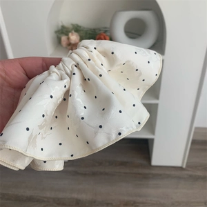 Detailed view of beige polka dot scrunchie with silk texture and rose jacquard pattern