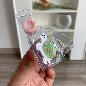 Detail shot of transparent tortoise hair claw with white turtle and pink button accent