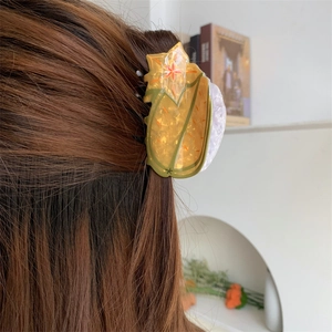 Floral acetate shark hair claw clip in yellow with orange flower patterns on brown hair