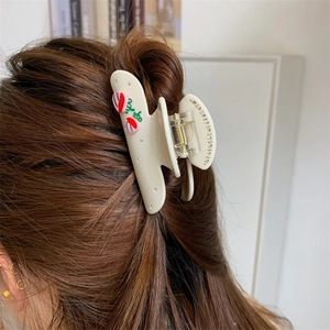 Detail einer cremefarbenen Haarspange mit Erdbeeren und Kristallen in braunem Haar