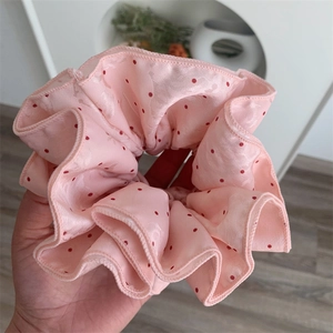 Close-up of pink polka dot silk-like fabric hair scrunchie with jacquard texture