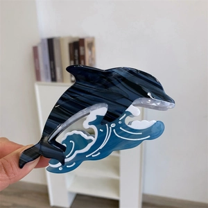 Détail de la pince à cheveux dauphin bleu en acétate avec une texture marbrée élégante