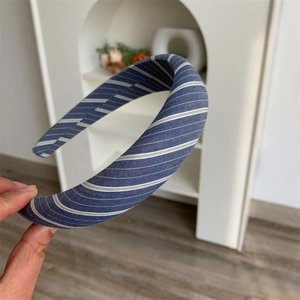 Detail of blue and white striped fabric padded headband held by hand for style