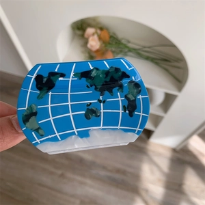 Detail of world map globe hair claw clip in blue acetate with green continents and grid