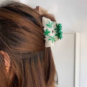 Detailed view of leaf pattern acetate hair claw clip worn by model on hair