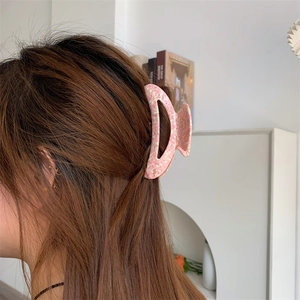 Detailed view of a pink marble texture hair claw clip holding long brown hair in a half-up style
