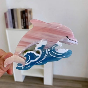Détail de la pince à cheveux dauphin avec texture marbrée rose et vagues d'océan bleues