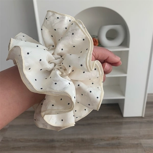 Detailed view of oversized polka dot scrunchie worn on wrist with satin texture