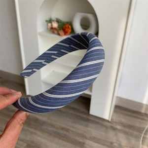 Close-up of a wide blue and white striped fabric headband with a padded sponge texture