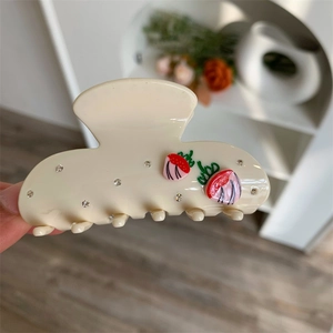 Detail einer großen cremefarbenen Haarklammer mit 3D-Erdbeeren und funkelnden Strasssteinen