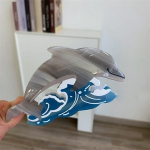 Détail de la pince à cheveux dauphin en acétate avec motif de vagues bleues et effet marbre