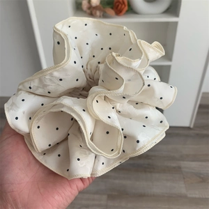 Close-up of beige polka dot scrunchie with layered ruffle design in lightweight fabric