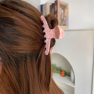 Detail of elegant pink acetate hair claw with marble texture shown on long hair