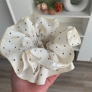 Close-up of beige polka dot oversized hair scrunchie with satin texture and jacquard detail
