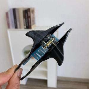 Détail d'une pince à cheveux en acétate motif requin avec un ressort doré robuste