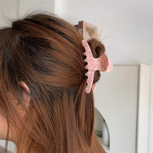 Pink marble texture acetate hair claw clip worn on a woman's hairstyle from side back view