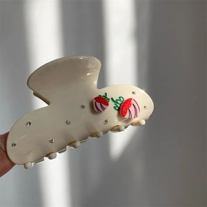 Nahaufnahme der cremefarbenen Haarklammer mit 3D-Erdbeeren und Kristalldetails