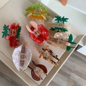 Detailed close-up of colorful acetate fruit-shaped hair claws on a textured display tray