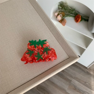 Close-up of strawberry-shaped acetate hair claw clip with detailed seeds and green leaves