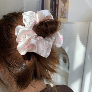 Detailed close-up of a large pink satin bow scrunchie worn on a woman's bun hairstyle