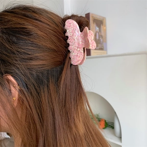 Detailed view of a pink marble textured acetate claw clip on brown tied hair
