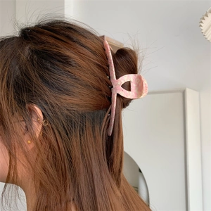 Detail view of a pink marble texture acetate hair claw clip worn in a low ponytail style