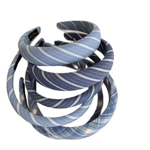 Three blue plaid and striped padded headbands stacked on a clean white background