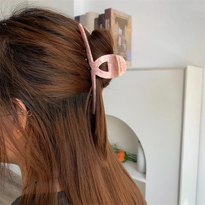 Close-up of pink peach texture hair claw clip worn by a model in a natural setting