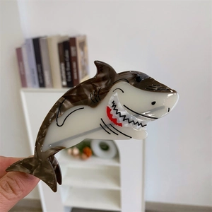 Détail d'une pince à cheveux requin en acétate marbré avec des détails de dents et bouche