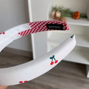 Detailaufnahme des Stoff-Haarreifs mit rotem Kirschmuster und handgefertigtem Etikett