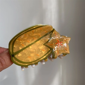 Detailed view of yellow starfruit hair claw clip made of translucent acetate material