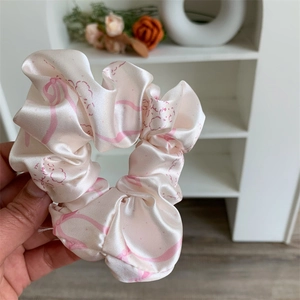 Detailed view of large satin hair scrunchie with pink character pattern and lace trim