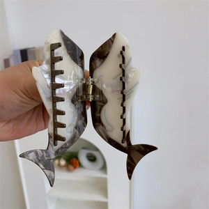 Détails d'une pince à cheveux en forme de requin en acétate avec un motif de marbre noir et blanc