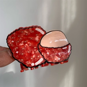 Detail view of a creative lychee-shaped acetate hair claw clip with realistic texture