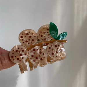 Detail of berry shaped acetate hair claw clip with vintage brown spots and green leaves