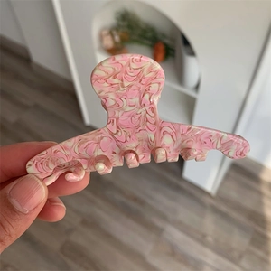 Close-up of pink peach texture acetate hair claw clip with marble finish and smooth teeth