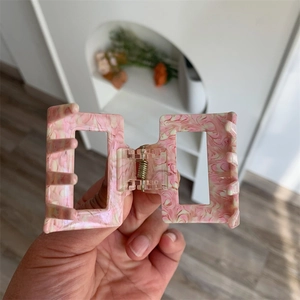 Detailed macro view of pink marble acetate hair claw clip with strong metal spring