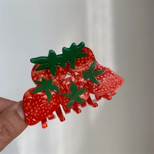Detail of creative strawberry shaped acetate hair claw clip with vibrant red finish